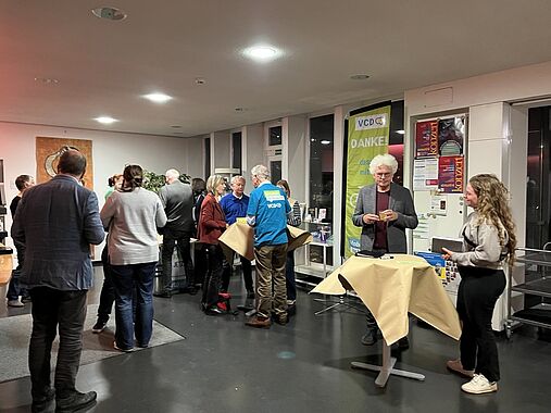 Menschen unterhalten sich in der Pause im Haus der Kirche an Stehtischen